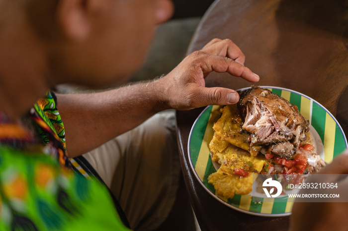 Imagen horizontal de cerca de un hombre irreconocible degustando una deliciosa comida caribeña en su