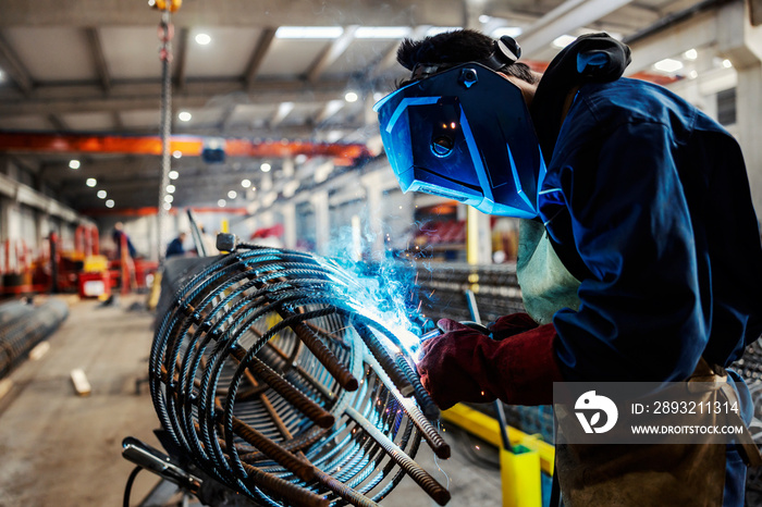 A heavy industry metal worker welding armature in factory.