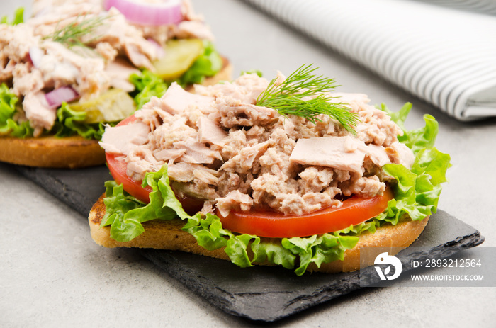 金枪鱼三明治配生菜、西红柿、泡菜和洋葱，放在石板托盘上