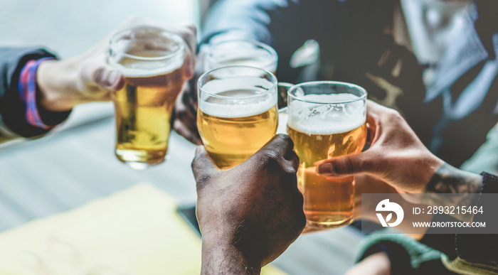 Group of multiracial friends enjoying a beer glasses in brewery english pub - Young people cheering 