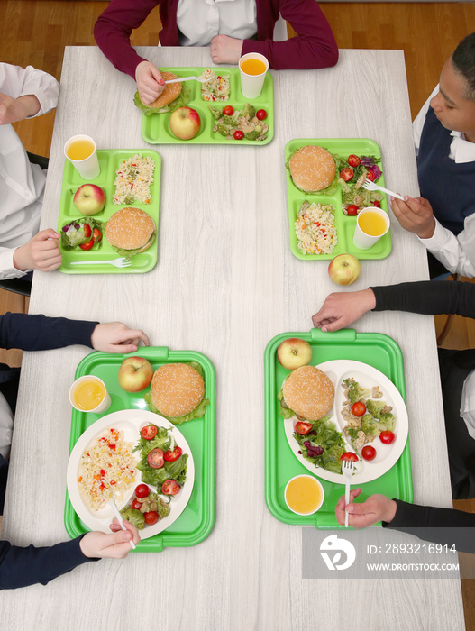 Children sitting at table in school cafeteria while eating lunch