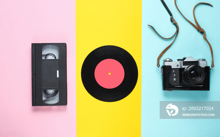 Retro still life. Vinyl record, vintage film camera, video cassette on colored background. Top view.