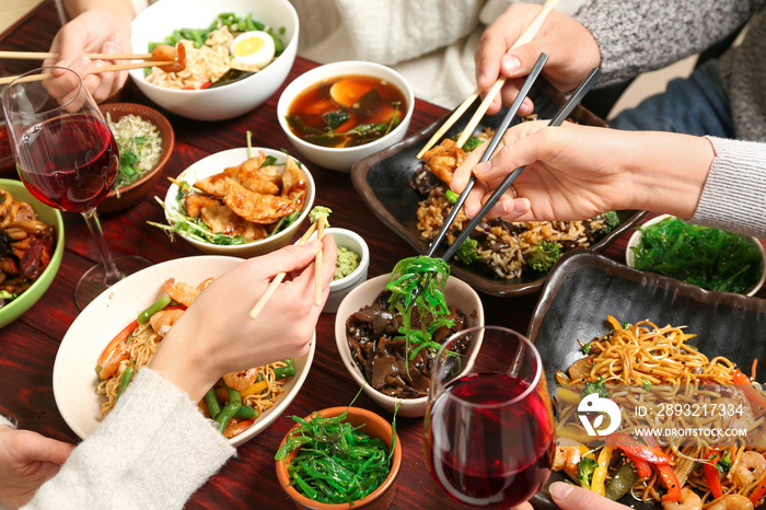 Friends eating tasty Chinese food at table