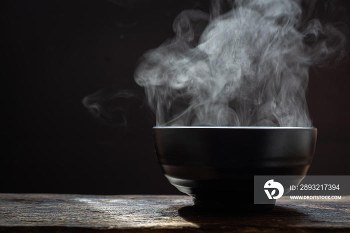 Hot food concept.Bowl of hot soup. steam of hot soup with smoke wood bowl on dark background.selecti