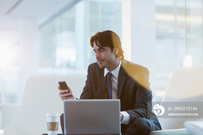 Corporate businessman using smart phone at laptop