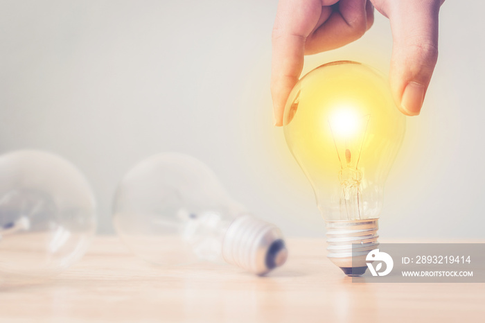 Hand holding light bulb on wooden desk. Concept new idea with innovation and creativity