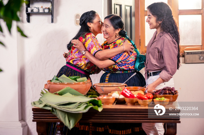 Abuela hija y nieta preparando tamales para fiesta familiar.