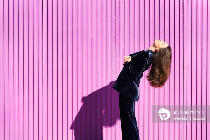 Woman wearing blue suit posing near pink shutter.