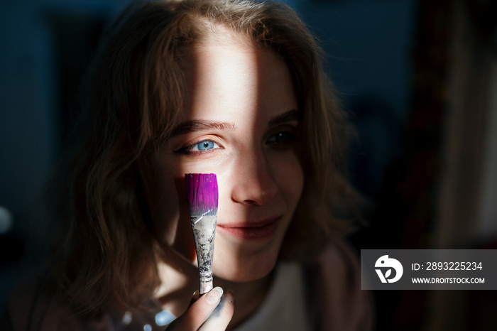 蓝眼睛的艺术家女孩用粉色颜料在脸上作画