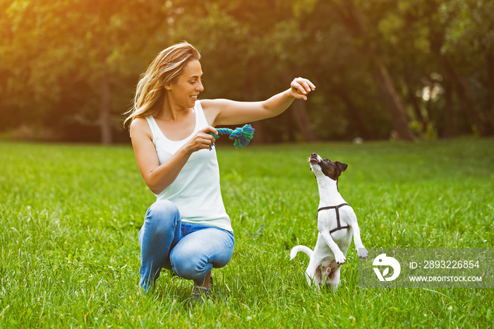 美丽的女人喜欢和她可爱的小狗杰克罗素梗在大自然中玩耍。