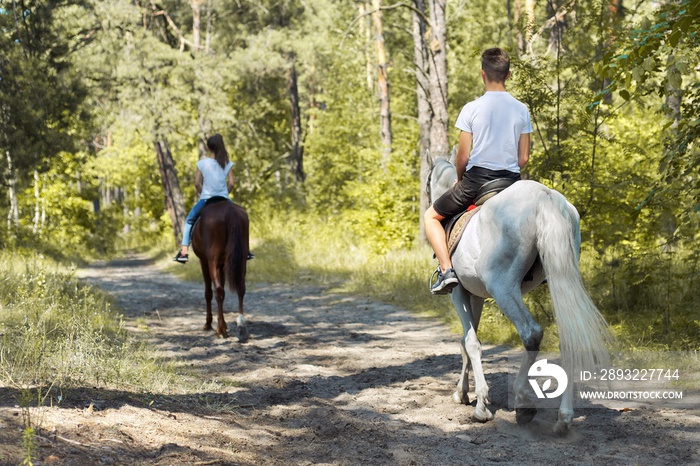 Group of teenagers on horseback riding in summer park