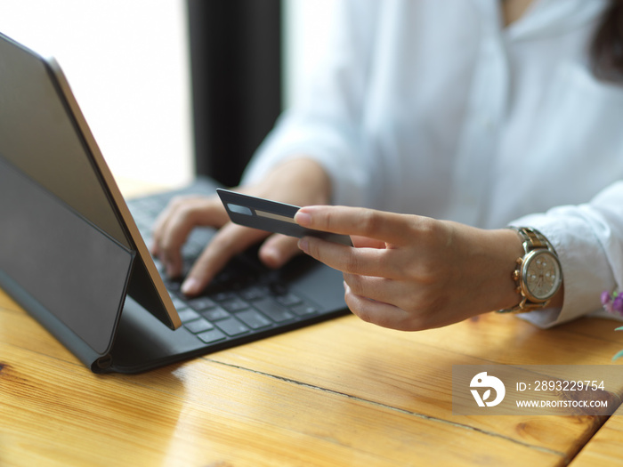 Female hand holding credit card while online paying on digital tablet