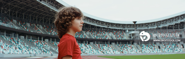 可爱的小男孩足球运动员站在空荡荡的体育场上，梦想成为职业球员