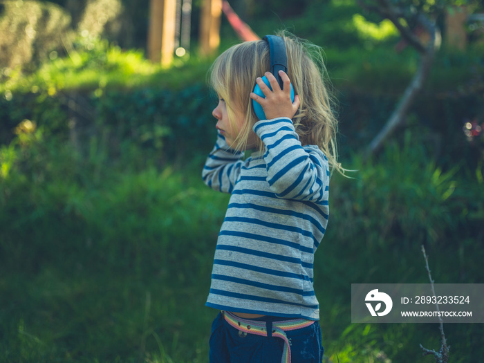 Toddler with ear defenders in garden