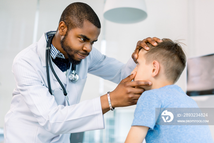 英俊的非洲男医生在诊所检查一个小男孩的眼睛。