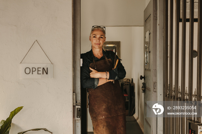 Female goldsmith standing at workshop door