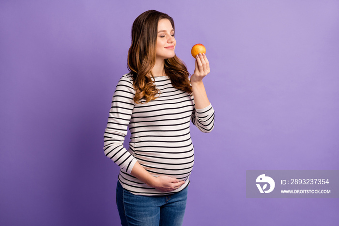 Photo of pretty dreamy lady waiting baby dressed striped shirt arm tummy enjoy fruit aroma isolated 