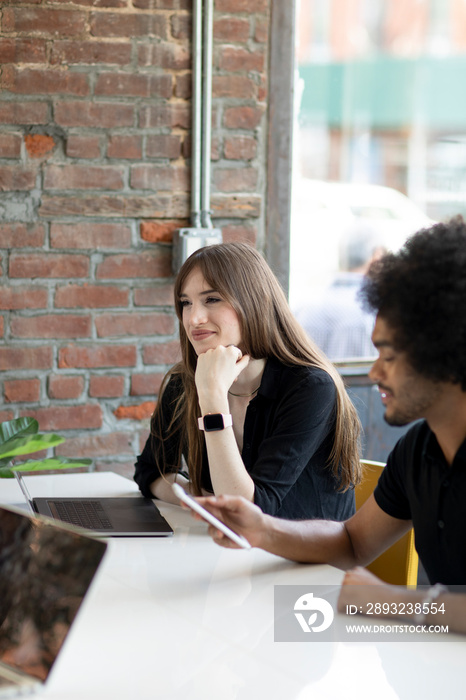 Young male and female coworkers sitting together at desk in creative office