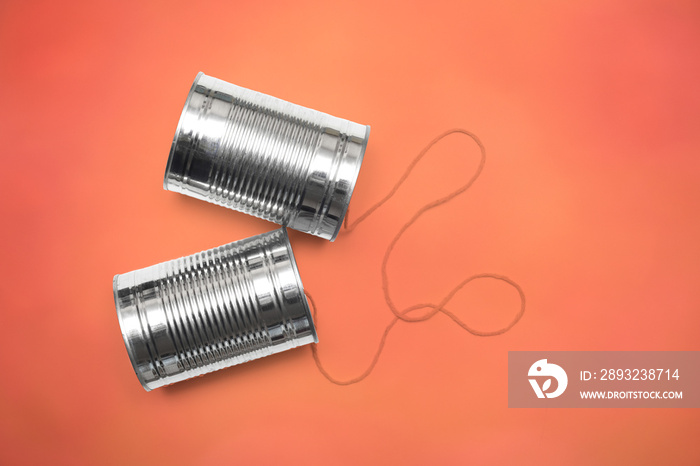 Communications and business calls concept of tin can telephone with string on orange