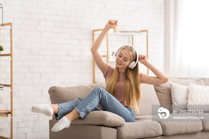 Joyful girl listening to music and dancing at home