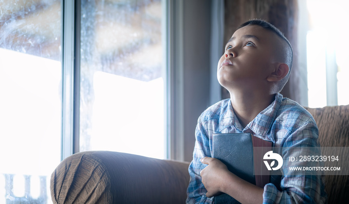 a boy look up and embrace bible, listening to the voice of God, religion concept.