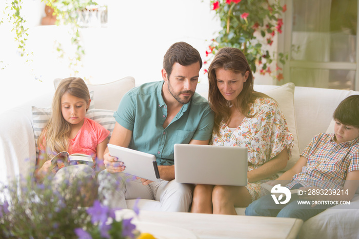 Family reading books and using laptop and digital tablet on patio