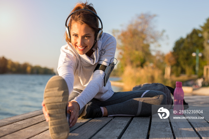 Beautiful young woman working out outside by the water