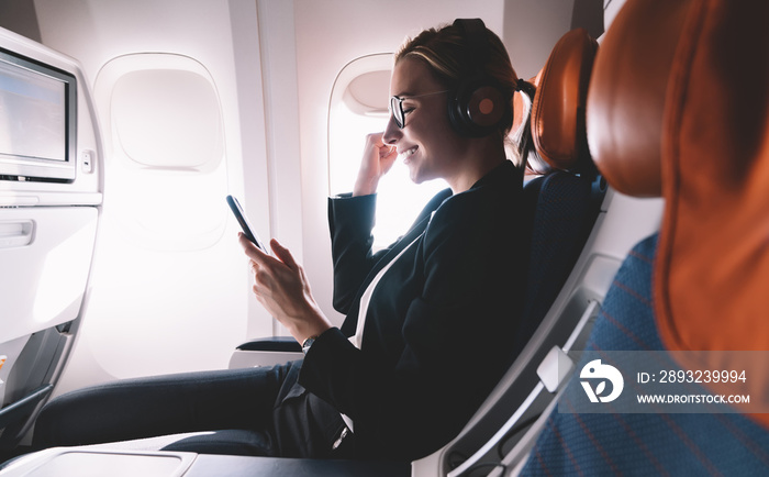 商务舱飞行中使用智能手机的满意女性
