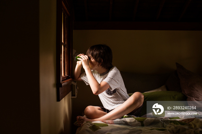 Boy looking through window with binoculars