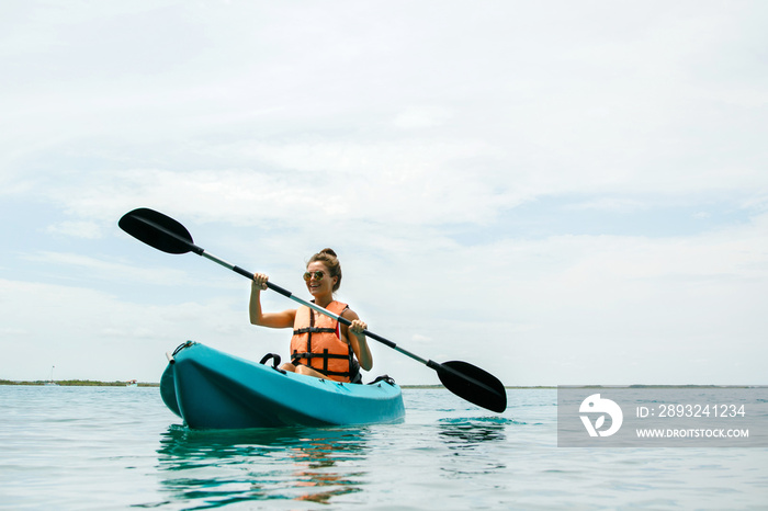 Happy young woman kayaking on the lake