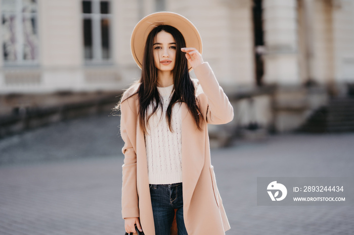 Young woman in a coat walking on the city street.