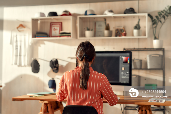 Taking ideas seriously. Portrait of female worker sitting by desk, drawing sketches logo design usin