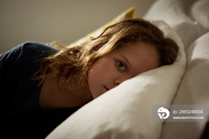 Portrait of serious girl lying on bed at home