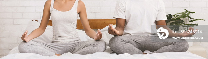 Young black family meditating in bed together