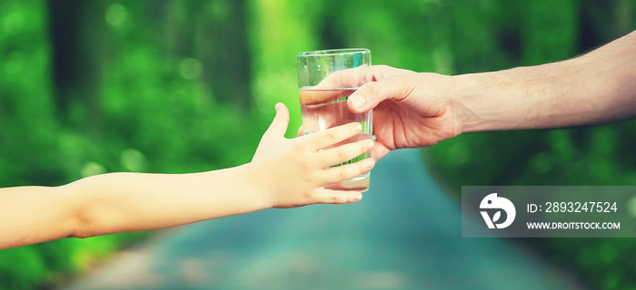 The father gives the child a glass of fresh water. Selective focus.