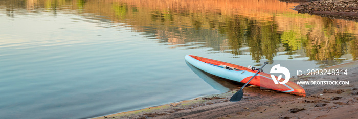 Long and narrow racing stand up paddleboard on a calm mountain lake in late summer - Horsetooth Rese