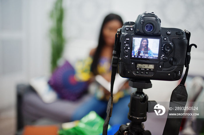 可爱的非裔美国妇女用三脚架数码相机为她的博客制作视频。年轻