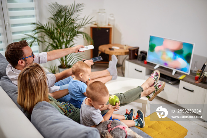 Young parents watching TV with baby boys.