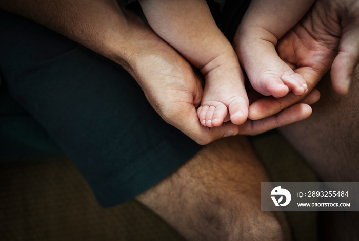 Father holding his baby sons (2-5 months) feet