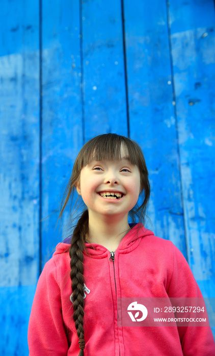 年轻女孩在蓝色墙壁的背景上微笑