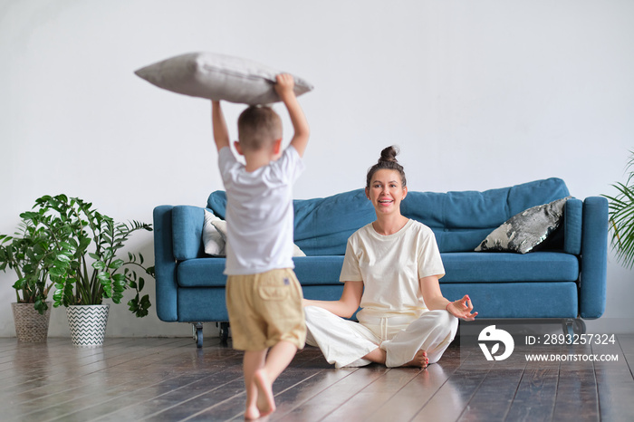 mother meditating for stress relief and emotional balance relaxing in living room with child. single