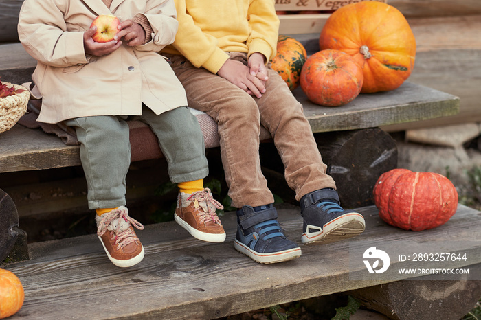 two sitting in autumn clothes on the steps next to a pumpkin