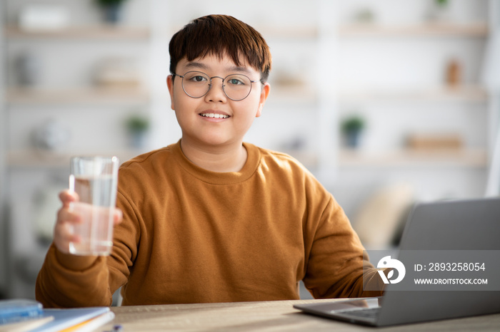 健康的亚洲青少年在学习时拿着一杯水