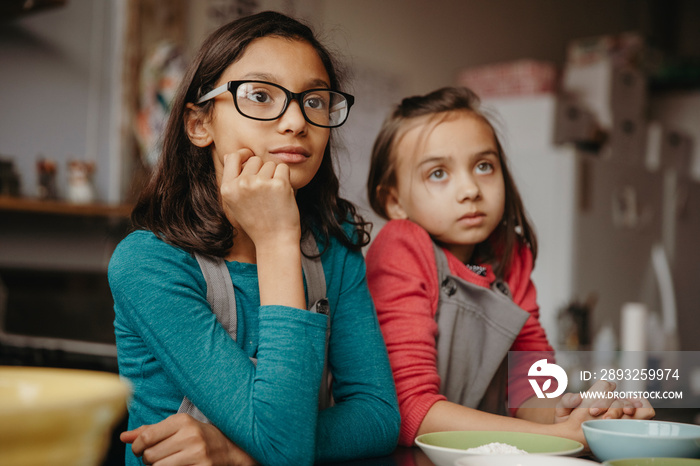 Thoughtful cute friends looking away while standing by table in training class