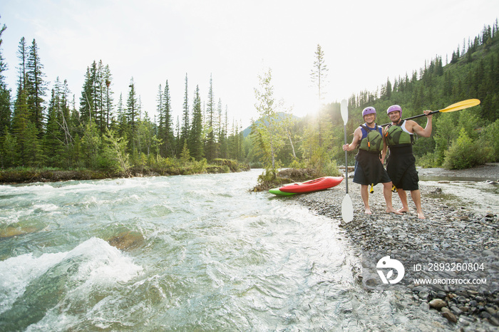 two male kayakers standing by a fast moving river