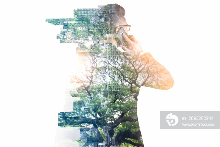 The double exposure image of the businessman using a smartphone during sunrise overlay with nature a