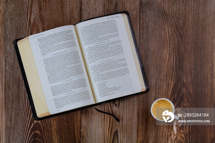 Open Bible morning readings on a table top with coffee cup