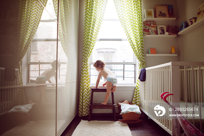 Shirtless girl looking through window at home