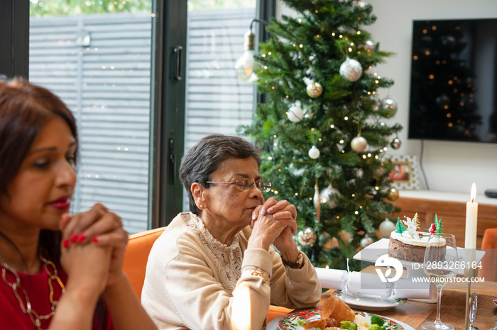 Women praying during Christmas dinner