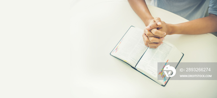 Woman hands closed in prayer on an open bible. Female  praying, hands clasped together on  Bible boo